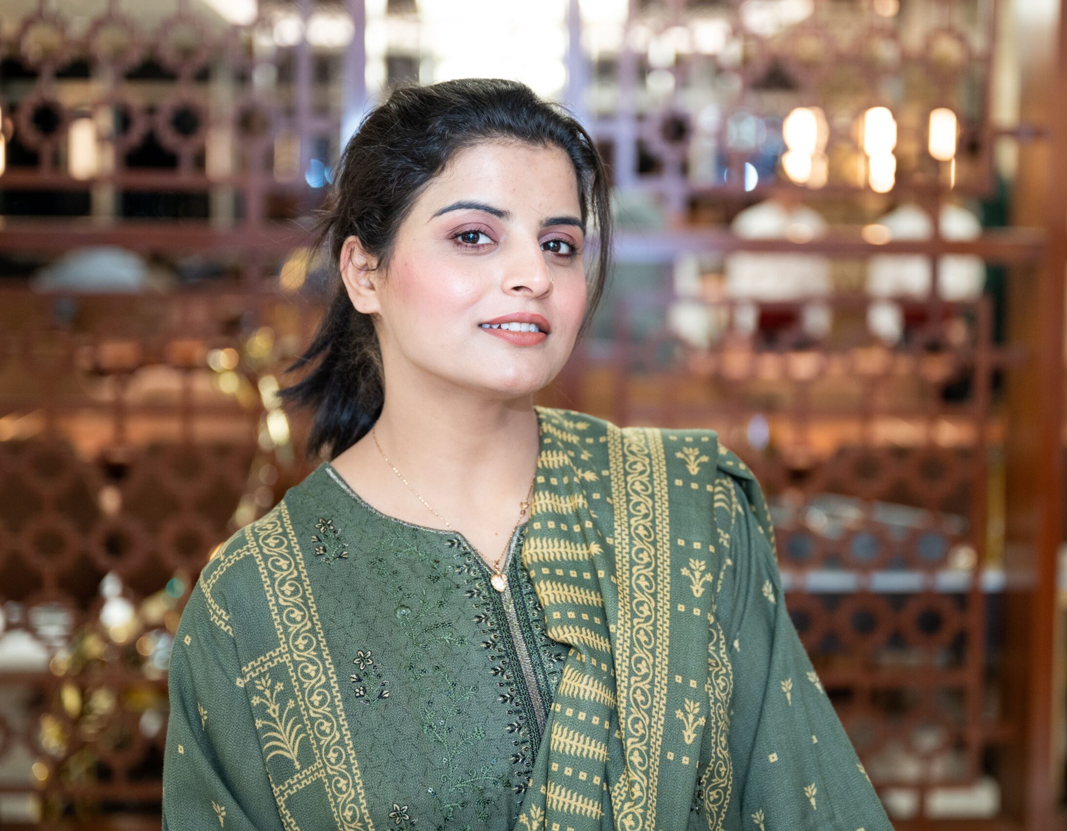 Elegant portrait of a woman in a green traditional dress indoors.